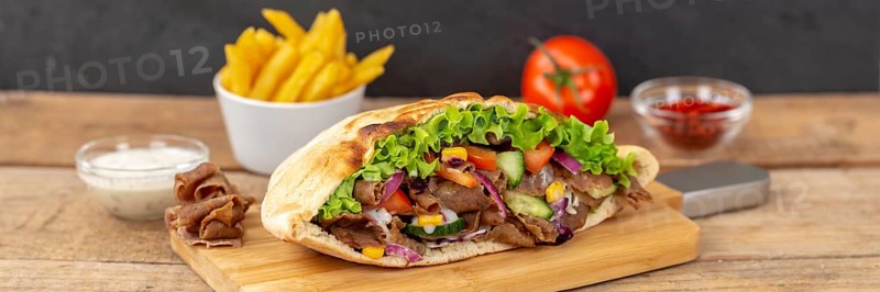 Doener Kebab Doner Kebap half fast food meal in pita bread with fries on wooden board Panorama in Stuttgart