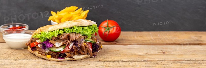 Doener Kebab Doner Kebap fast food meal in pita bread menu with fries on wooden board Panorama with text free space Copyspace in Stuttgart