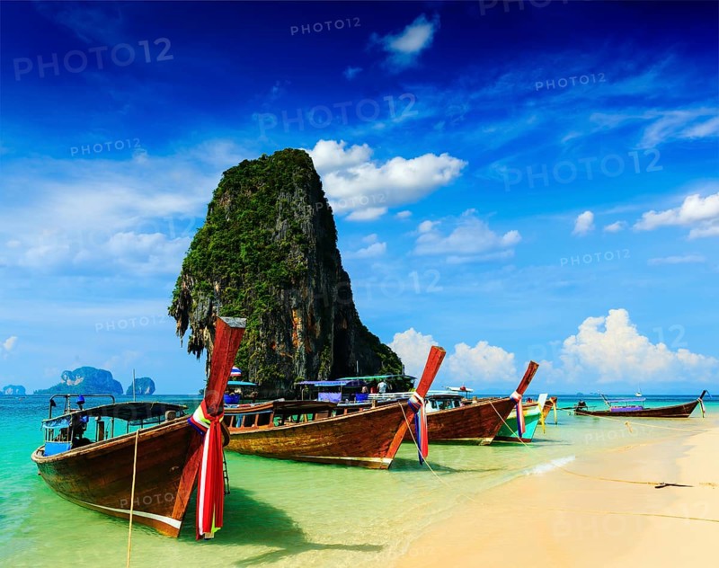 Long tail boat on tropical beach with limestone rock