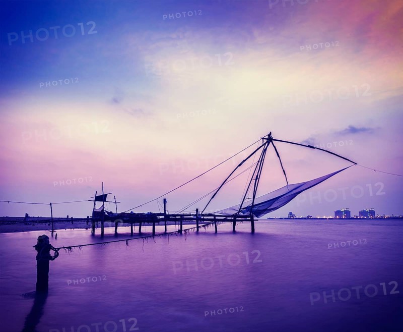 Vintage retro hipster style travel image of Kochi chinese fishnets on sunset. Fort Kochin