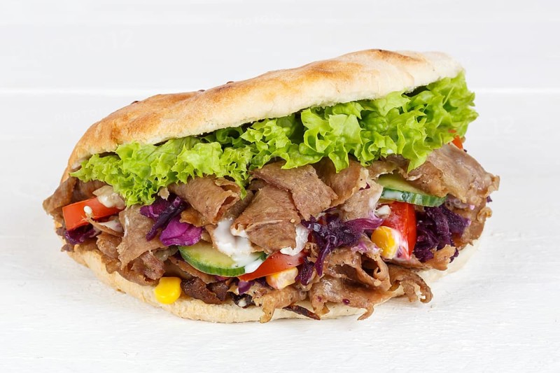 Doener Kebab Doner Kebap half fast food meal in pita bread panorama on wooden board in Stuttgart