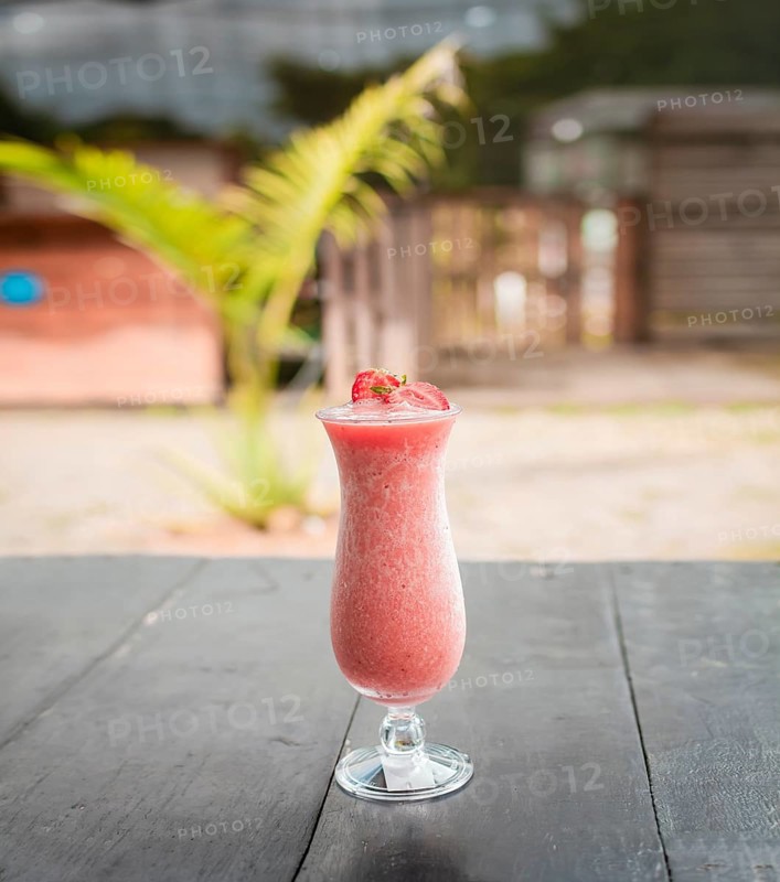 Close up of healthy strawberry smoothie on wood with blurred background