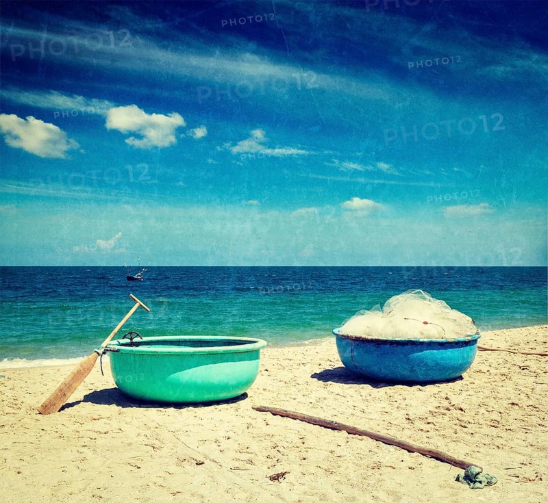 Vintage retro hipster style travel image of fishing coracle boats on beach with grunge texture overlaid. Mui Ne