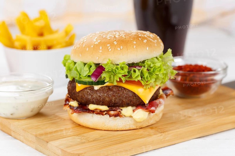Hamburger cheeseburger fast food meal menu with fries and coke drink on wooden board in Stuttgart
