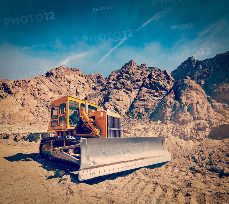 Vintage retro effect filtered hipster style travel image of Bulldozer doing road construction in Himalayas. Ladakh