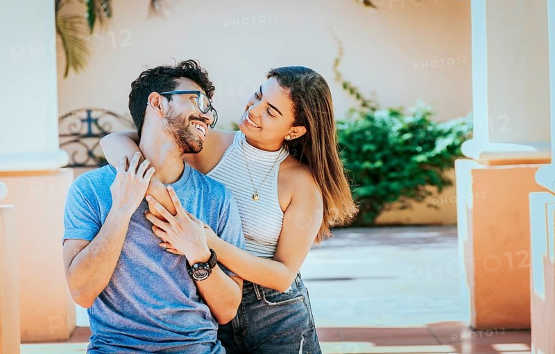 Girl hugging her boyfriend from behind. Smiling woman hugging her boyfriend from behind while he smiles at her