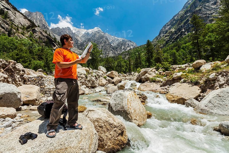Hiker trekker studying map route on trek in Himalayas mountains. Himachal Pradesh