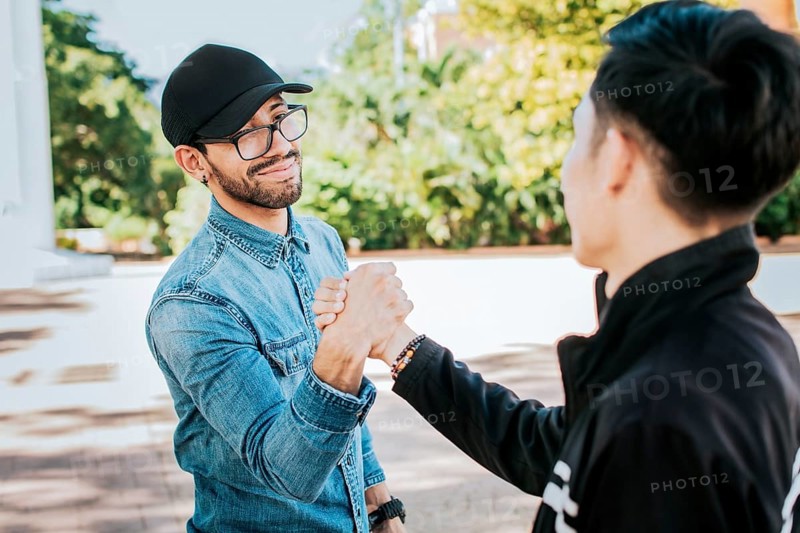 Two happy friends shaking hands in the street. Two people shaking hands on the street. Two smiling friends greet each other on the street