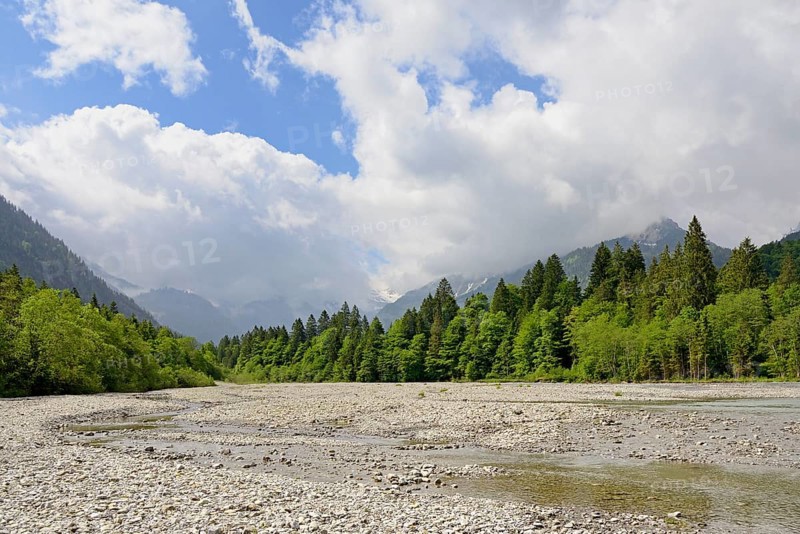 View of the Stillach river landscape and the cloud-covered mountains