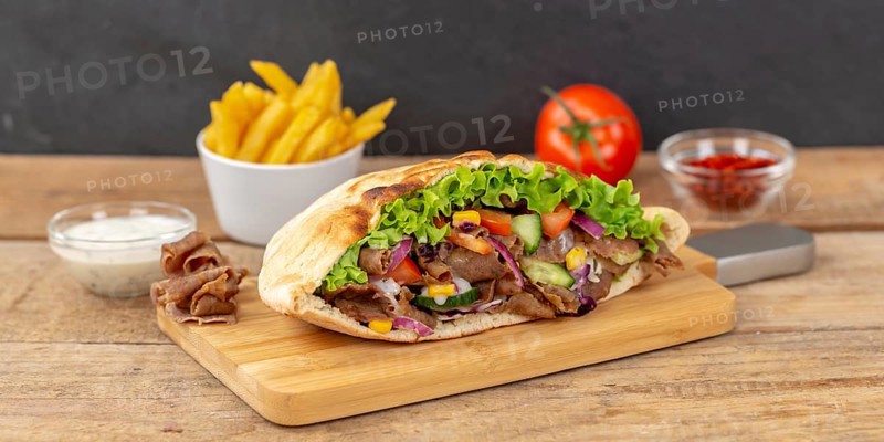 Doener Kebab Doner Kebap half fast food meal in pita bread with fries on wooden board Panorama in Stuttgart