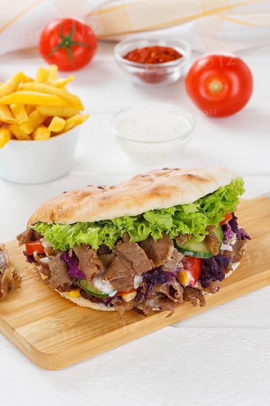 Doener Kebab Doner Kebap fast food meal in pita bread menu with fries on kitchen board in Stuttgart