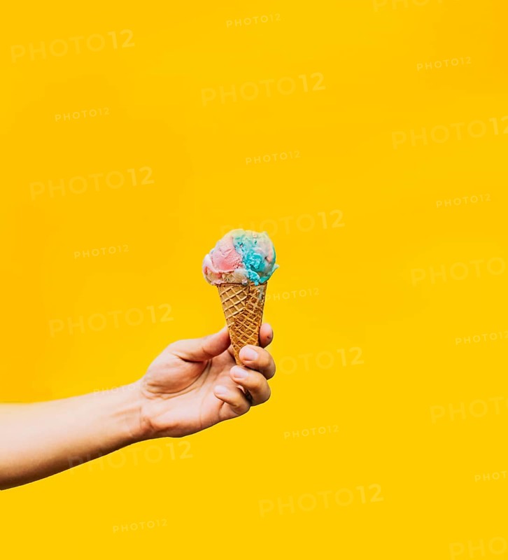 Hand holding ice cream cone on yellow background. Hand holding a waffle cone ice cream isolated. Waffle cone ice cream concept on yellow background