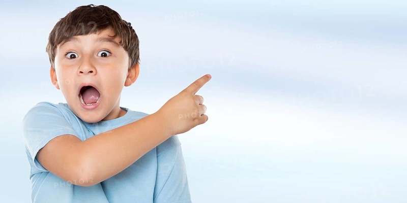 Child boy is amazed surprised points to advertising success with copy space Copyspace in Stuttgart