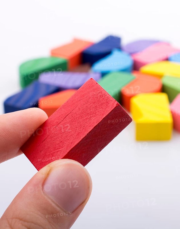 Colorful wooden pieces of a logic puzzle in hand