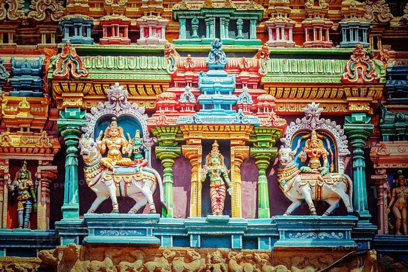 Vintage retro hipster style travel image of Shiva and Parvati on bull images. Sculptures on Hindu temple gopura tower. Minakshi Temple