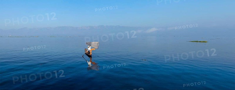 Panorama of traditional Burmese fisherman balancing with fishing net at Inle lake