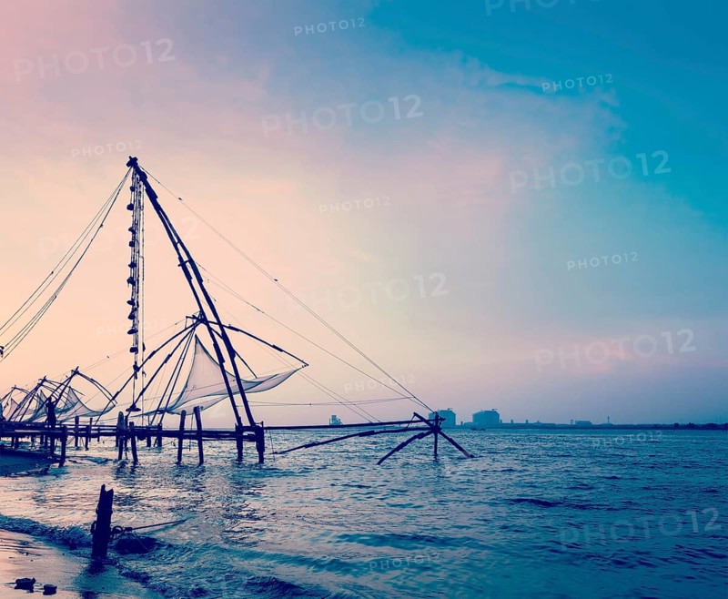Vintage retro hipster style travel image of Kochi chinese fishnets on sunset. Fort Kochin