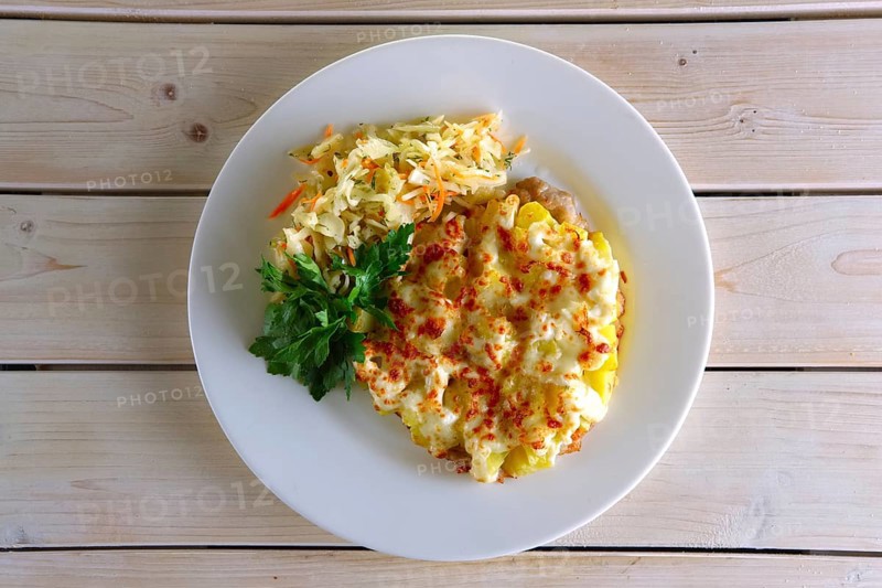 Chopped meat fillet with potato cubes covered with melted cheese and served with pickled cabbage and carrot