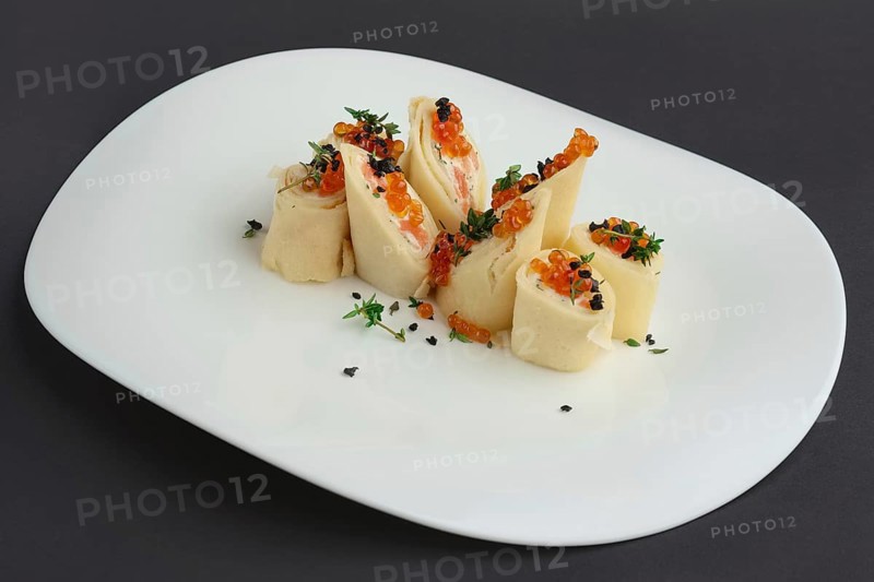 Pancakes with salmon and caviar on big white plate