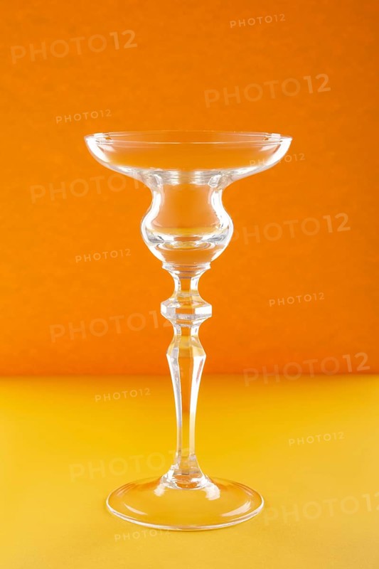 Empty glass for cocktail or dessert on orange background