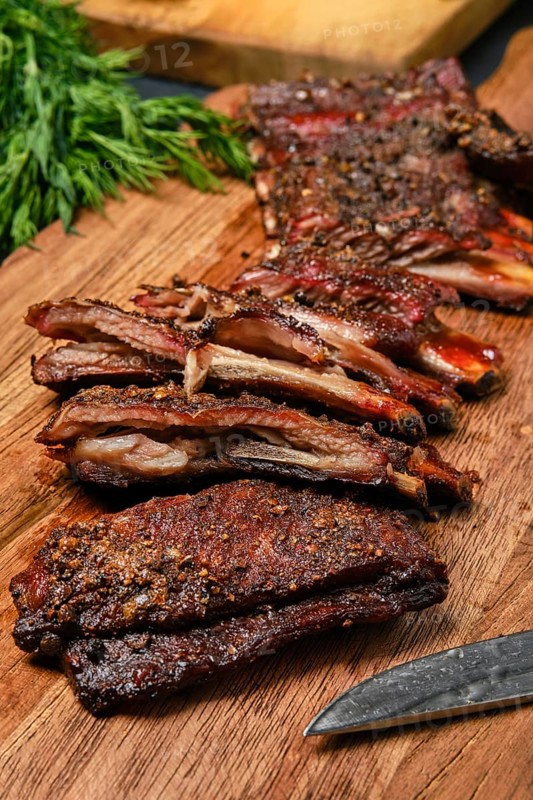 Top view of grilled lamb breast ribs on wooden cutting board