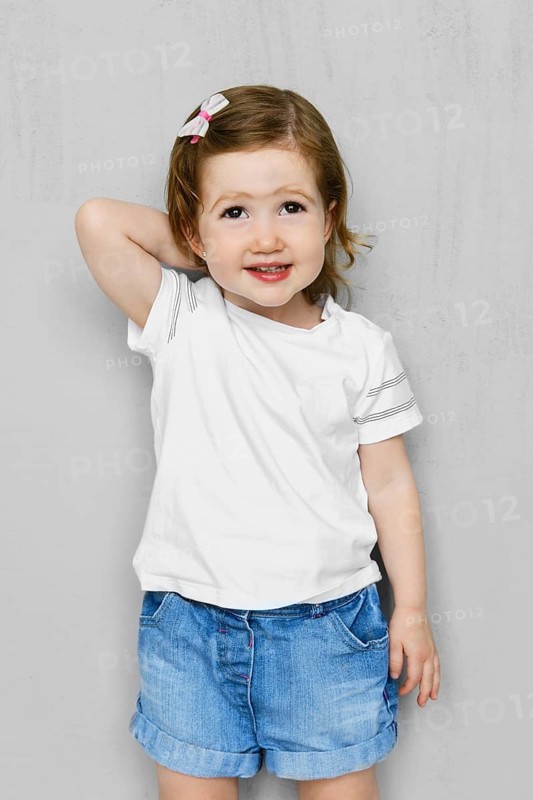 Two years old girl in white t-short and jeans shorts posing in studio