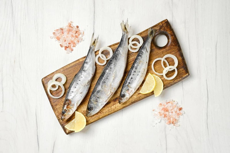 Top view of salted iwashi herring fish marinated in spice on wooden cutting board