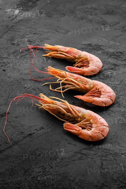Three fresh raw prawns on wooden background