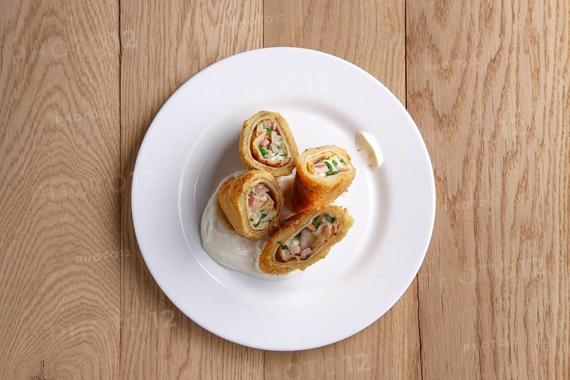 Top view of deep-fried pancakes stuffed with ham and covered with melted cheese