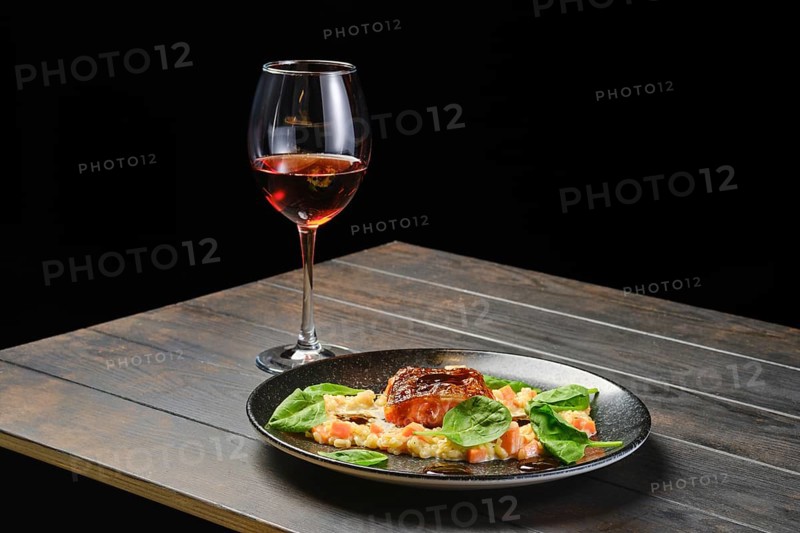 Roasted salmon fillet with bulgur with glass of rose wine on a table