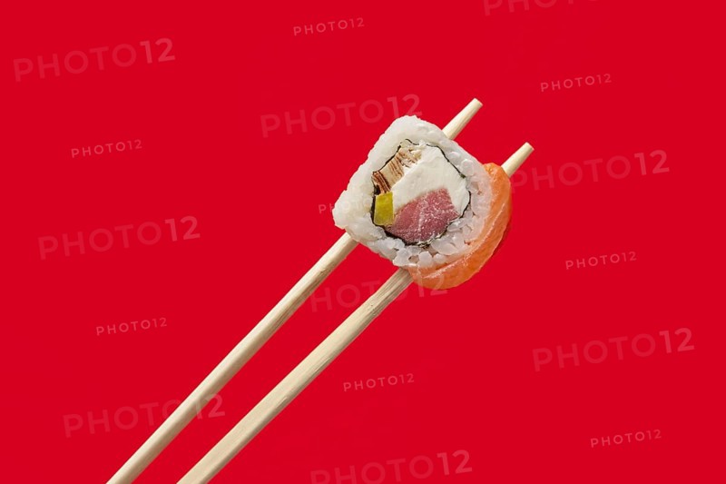 Holding roll with salmon and tuna on chopsticks