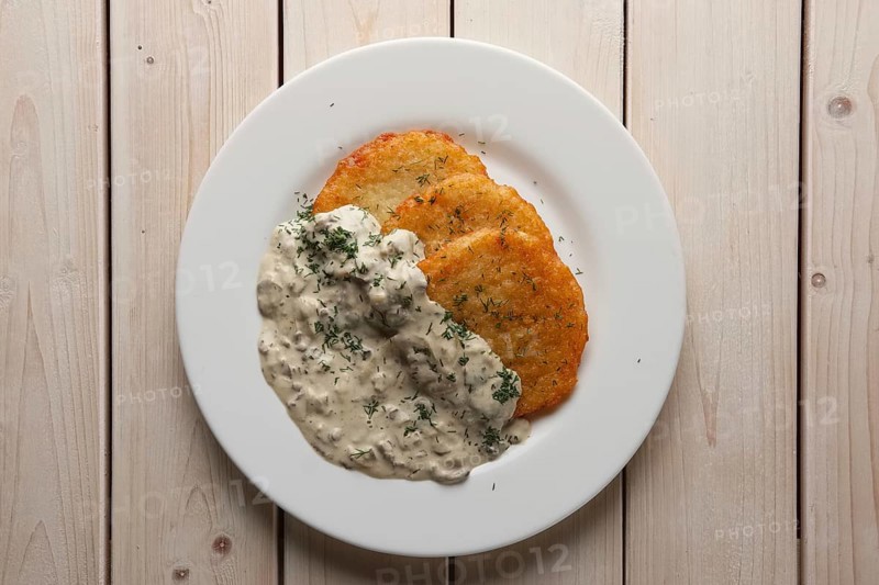 Traditional belorussian potato pancakes draniki with mushroom sauce on a plate