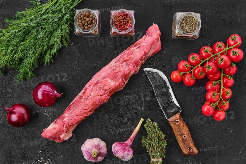 Top view of raw fresh pork fillet with spice on black background