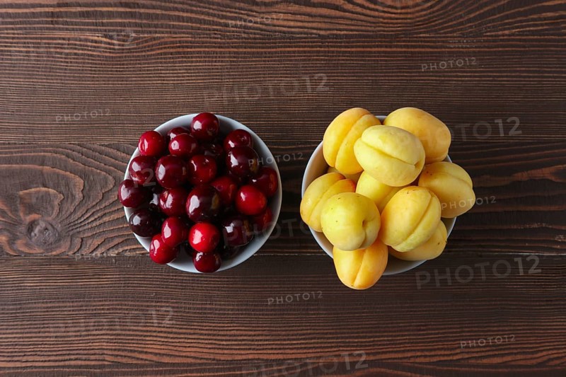 Cherries and apricots on dark wooden background