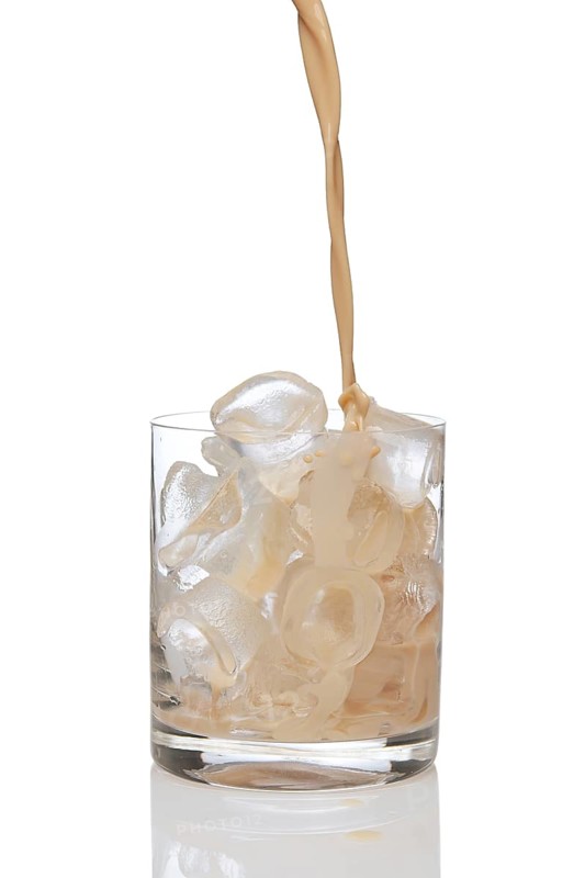 Irish creme liqueur pouring in a glass full of ice