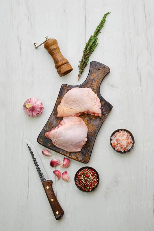 Raw chicken thighs on wooden cutting board ready for cooking