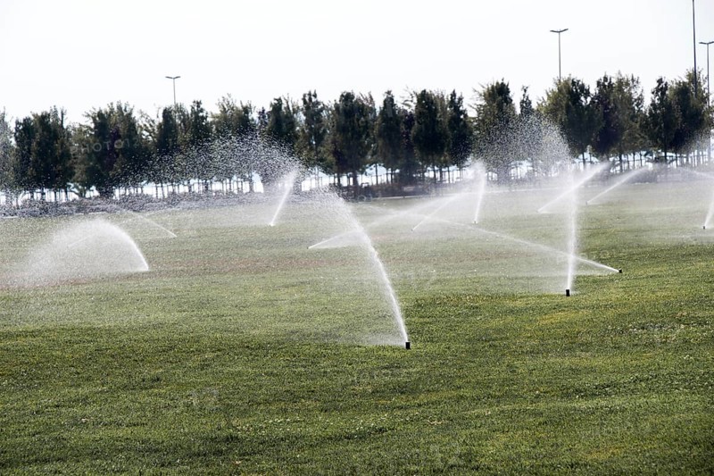 Lawn water sprinkler spraying water over grass in garden