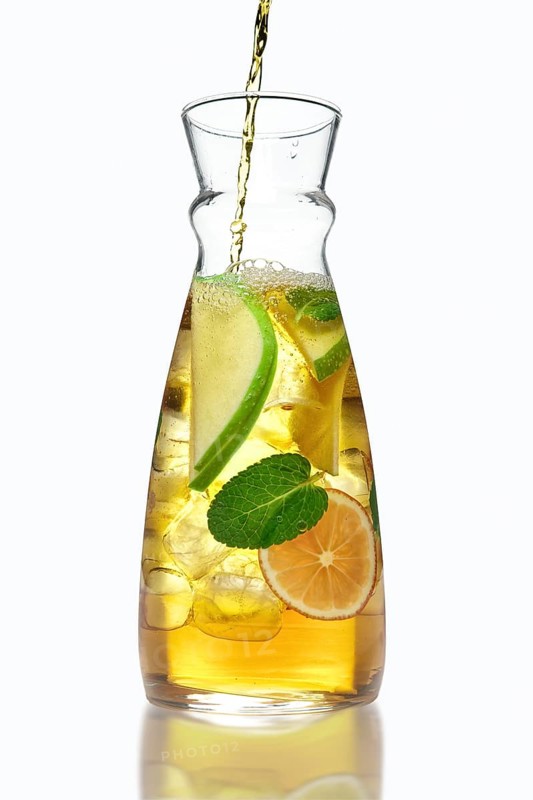 Filling up the jar with icy apple and orange drink with mint flavour