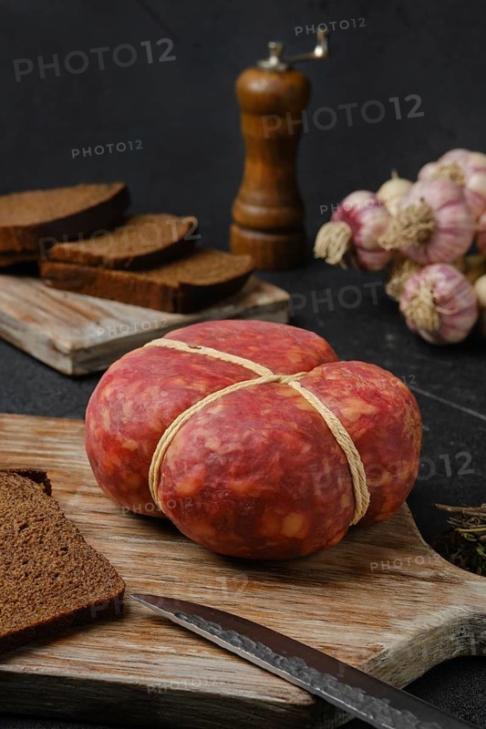 Smoked round beef sausage on cutting board over black background
