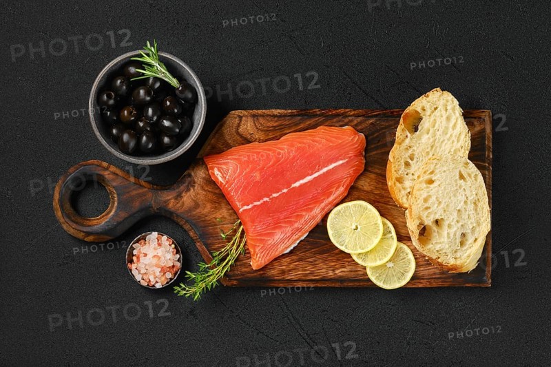 Top view of piece of fresh salmon tail fillet with ciabatta and spicy herb sauce