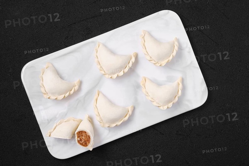 Top view of frozen dumplings stuffed with beef meat and provencal herbs on marble serving plate