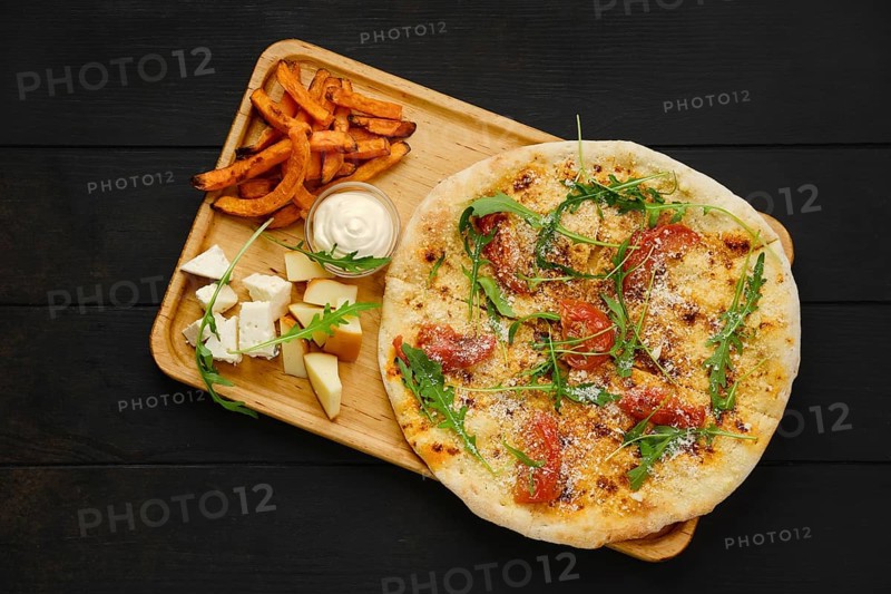 Top view of focaccia with tomato and parmesan served with cheese and fried sweet potato on wooden tray