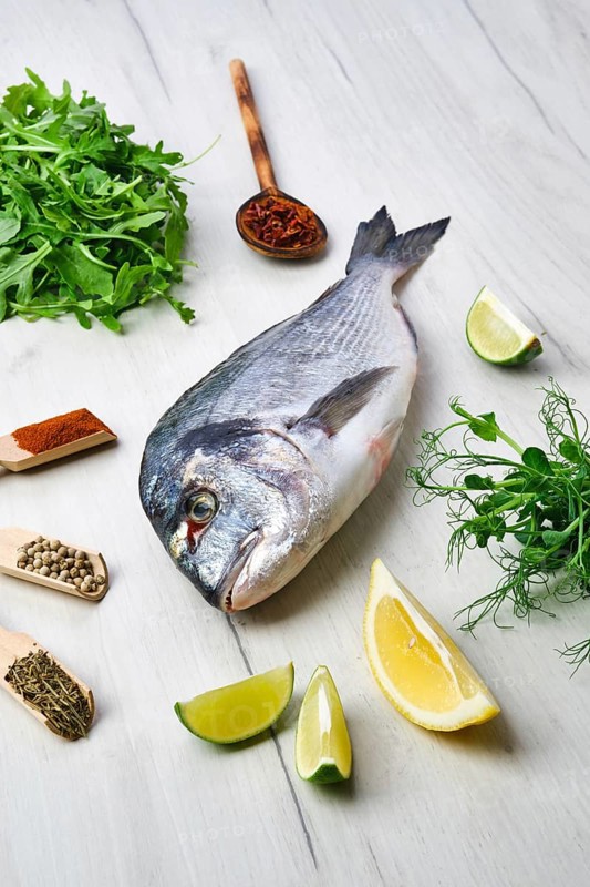 Dorada fish on the table with spice and herbs
