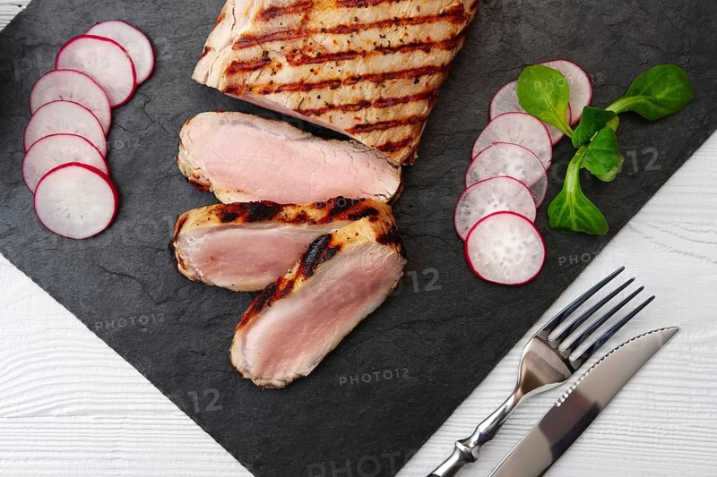 Sliced grilled pork fillet with fresh tomatoes and raddish served with glass of red wine
