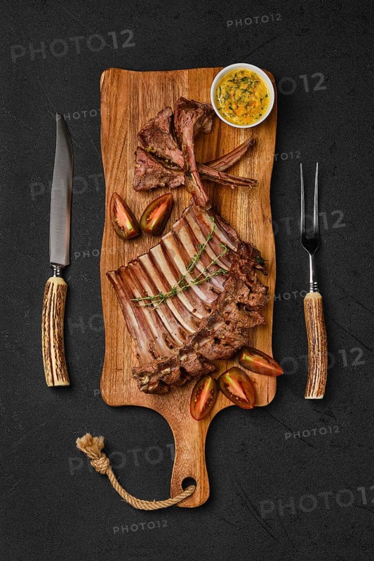 Overhead view of grilled ribs of lamb on a plate with spicy sauce