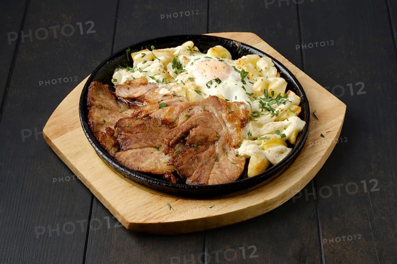 Fried pork t-bone chop with potato and egg on a plate