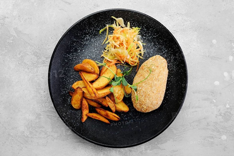 Cutlet stuffed with cheese served with fried potato wedges and sauerkraut