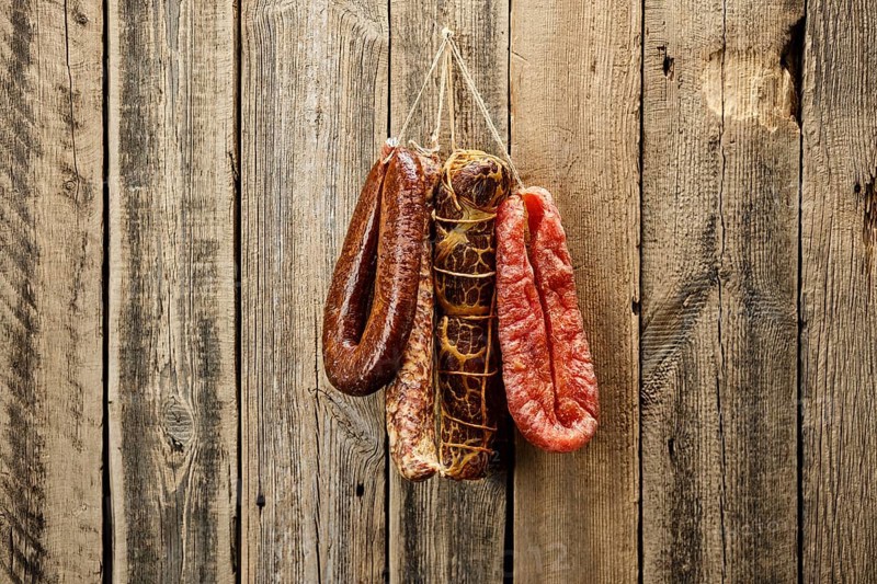 Assortment of dried meat and sausages hanging on a barn wall