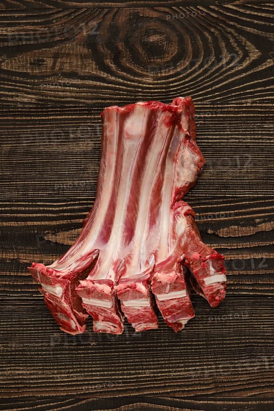 Overhead view of raw fresh doe ribs over dark wooden background