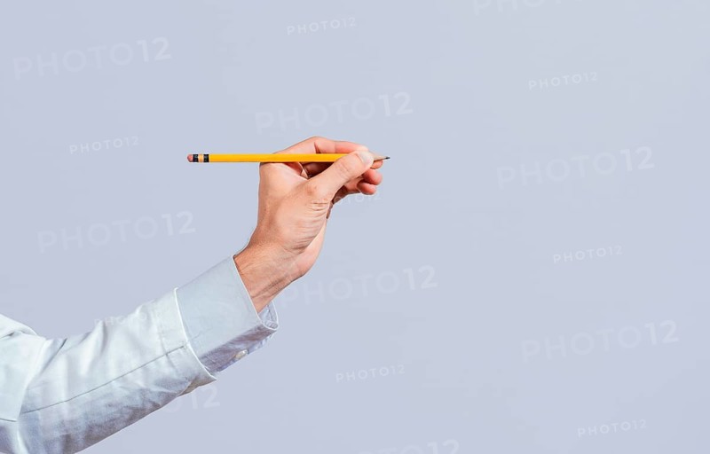Male hand holding a pencil on a blank. Man fingers holding a pencil with blank space. Person hands holding a pencil on a space for text